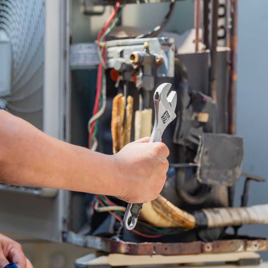 Blogs 1 Professional HVAC technician repairing an outdoor air conditioning condenser unit in Warwick RI