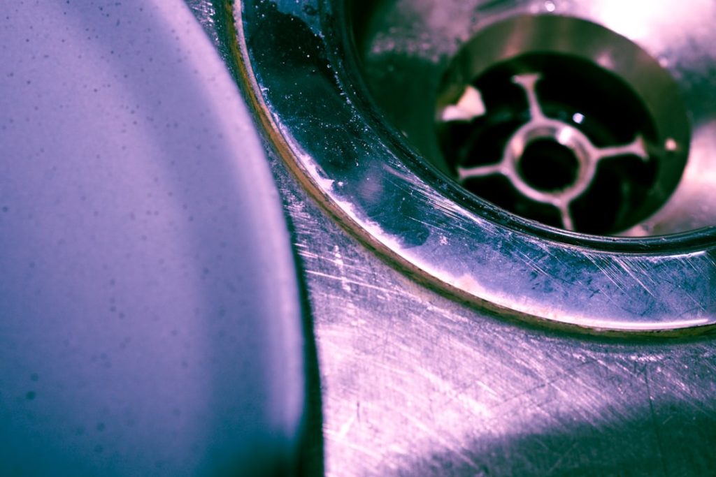 clogged sink with standing water and drain cleaner bottle